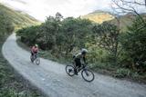Rider follows his guide during a guided gravel bike holiday in Peru. They enjoy beautiful scenery along a remote gravel road in the Yanatile Valley.