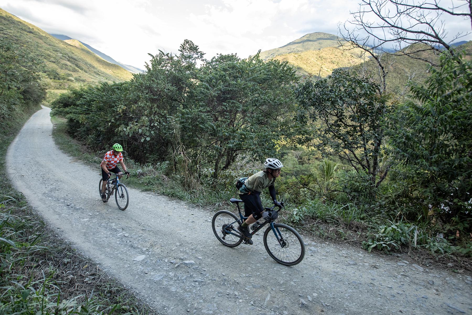 Rider follows his guide during a guided gravel bike holiday in Peru. They enjoy beautiful scenery along a remote gravel road in the Yanatile Valley.
